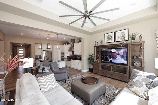 living area featuring a raised ceiling, recessed lighting, dark wood-style flooring, and baseboards