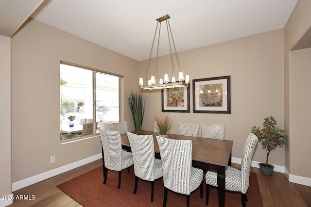 dining space with baseboards, a notable chandelier, and wood finished floors