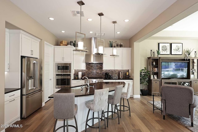 kitchen with dark countertops, dark wood-type flooring, decorative backsplash, appliances with stainless steel finishes, and a kitchen breakfast bar