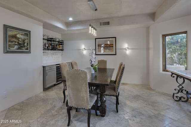 dining room featuring indoor bar and a tray ceiling