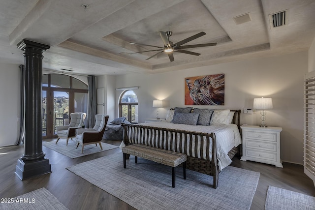 bedroom featuring a tray ceiling, dark hardwood / wood-style floors, ceiling fan, and ornate columns