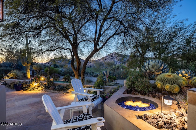 patio terrace at dusk featuring an outdoor fire pit and a mountain view