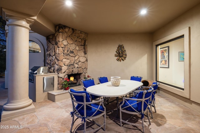 dining room with an outdoor stone fireplace and ornate columns