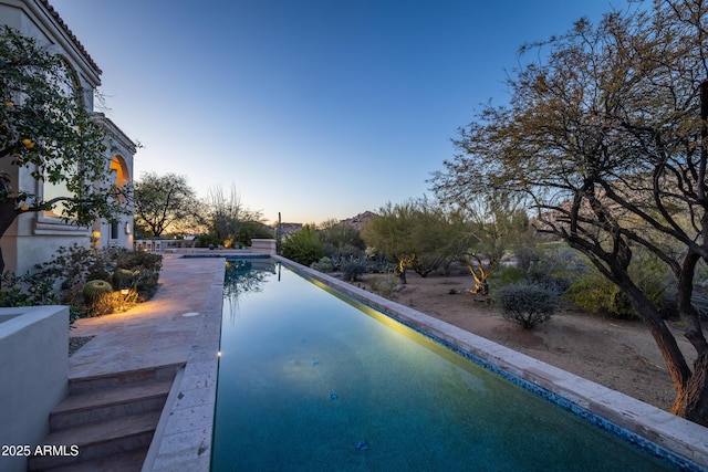 pool at dusk featuring a patio