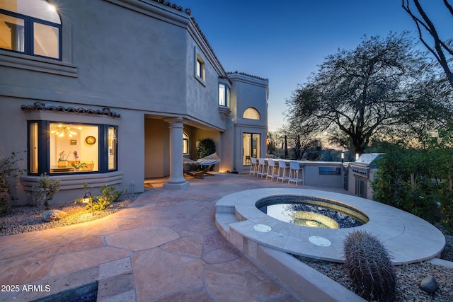 patio terrace at dusk featuring exterior bar and exterior kitchen