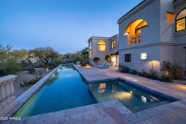 pool at dusk with a patio area