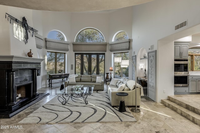 living room with a towering ceiling and a tile fireplace