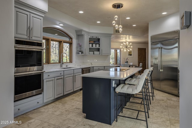 kitchen featuring sink, hanging light fixtures, gray cabinets, a kitchen island, and stainless steel appliances