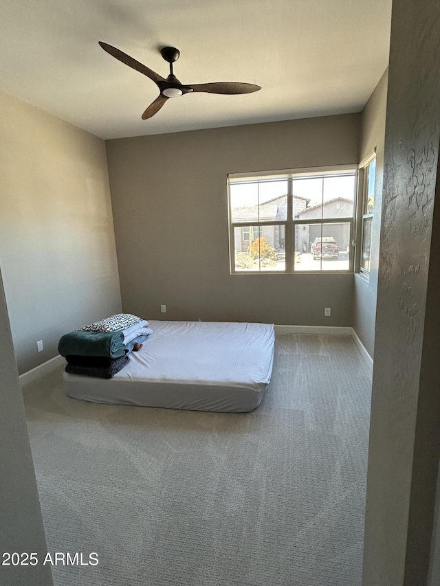 unfurnished bedroom featuring carpet, a ceiling fan, and baseboards