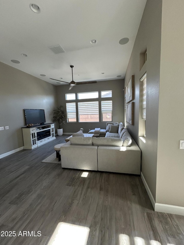 living area featuring visible vents, baseboards, ceiling fan, and wood finished floors