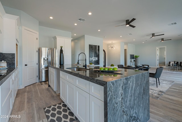 kitchen featuring white cabinets, a large island, stainless steel fridge, and sink