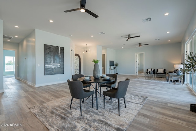 dining area featuring ceiling fan with notable chandelier and light wood-type flooring