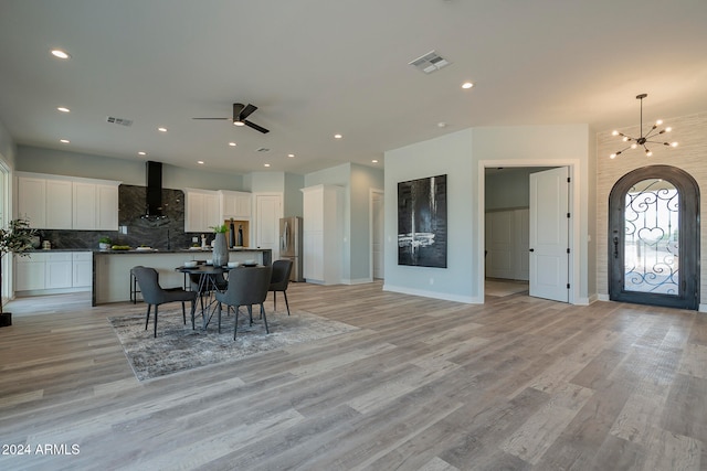 dining room featuring ceiling fan with notable chandelier and light wood-type flooring