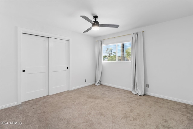 unfurnished bedroom with light carpet, a closet, and ceiling fan