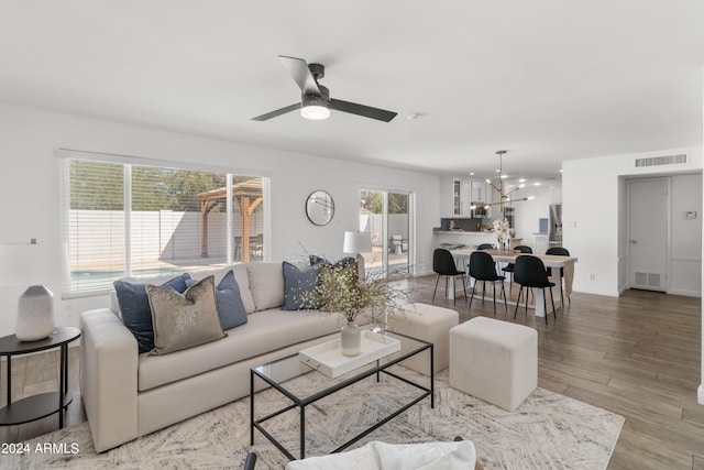 living room featuring wood-type flooring and ceiling fan with notable chandelier