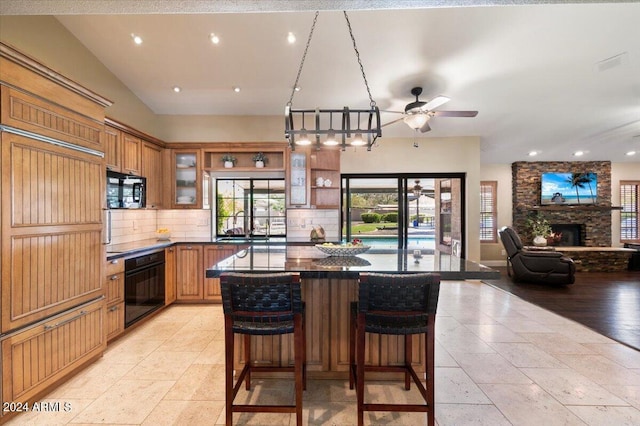 kitchen featuring tasteful backsplash, a large island, a breakfast bar, and black appliances