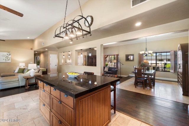 kitchen with a breakfast bar, lofted ceiling, a chandelier, hanging light fixtures, and a center island