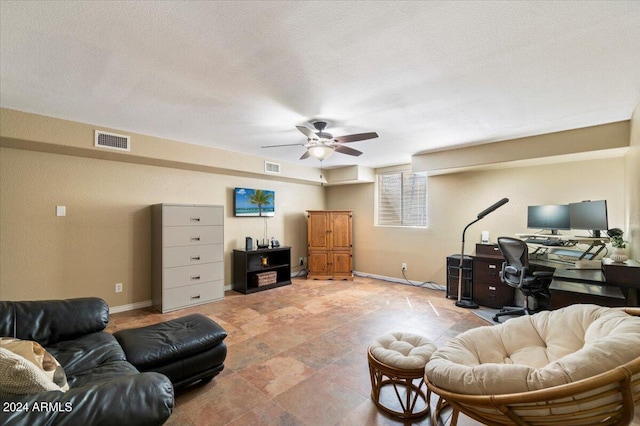 living room featuring ceiling fan and a textured ceiling