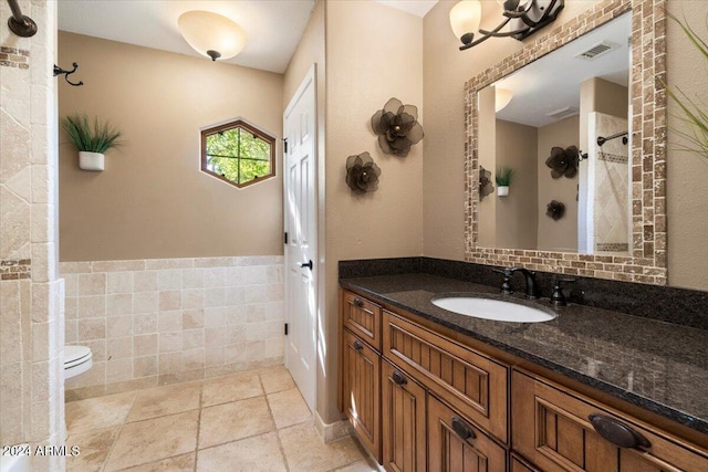 bathroom with vanity, toilet, tile walls, and a shower