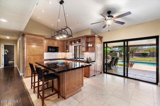 kitchen with a kitchen island, pendant lighting, high vaulted ceiling, backsplash, and a kitchen breakfast bar