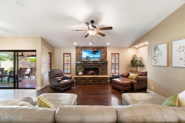 living room featuring wood-type flooring, a stone fireplace, lofted ceiling, and ceiling fan