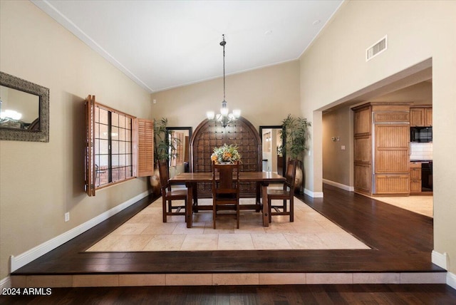 dining area with vaulted ceiling, an inviting chandelier, and light wood-type flooring