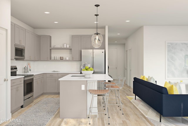 kitchen featuring pendant lighting, sink, light wood-type flooring, an island with sink, and stainless steel appliances