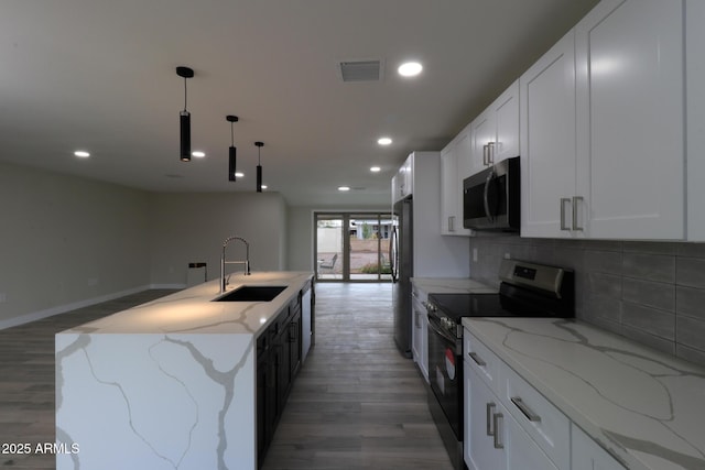 kitchen featuring visible vents, a kitchen island with sink, a sink, backsplash, and appliances with stainless steel finishes