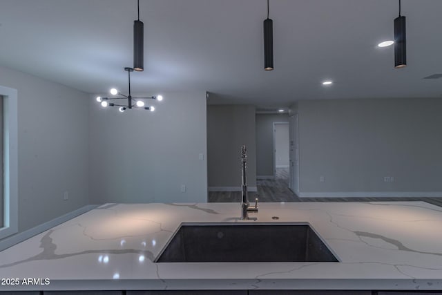 kitchen featuring a sink, open floor plan, recessed lighting, light stone countertops, and hanging light fixtures