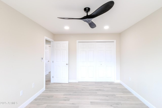 unfurnished bedroom featuring light wood-style floors, baseboards, and a closet