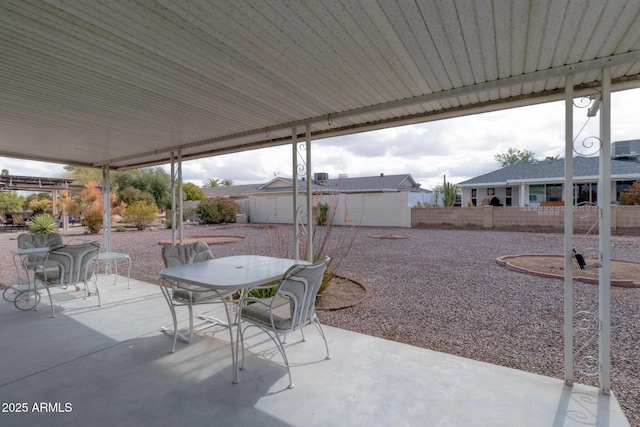 view of patio with an outbuilding, outdoor dining area, and fence