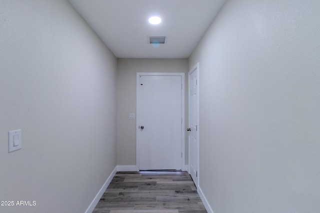 hall with wood finished floors, visible vents, and baseboards