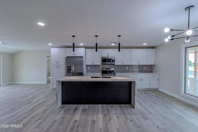 kitchen with decorative backsplash, white cabinets, light wood-style floors, and appliances with stainless steel finishes