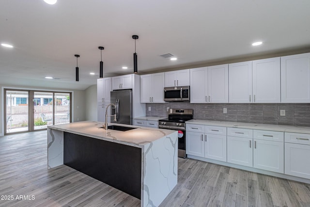 kitchen featuring visible vents, a sink, light wood-style floors, appliances with stainless steel finishes, and backsplash