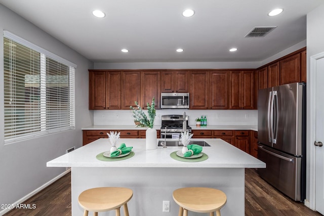 kitchen featuring sink, a breakfast bar area, dark hardwood / wood-style floors, an island with sink, and stainless steel appliances