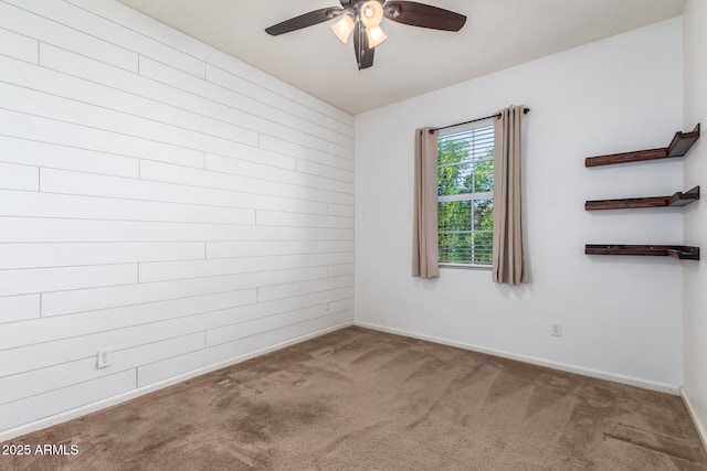 empty room featuring carpet, wooden walls, and ceiling fan