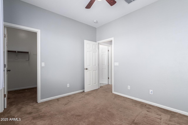 unfurnished bedroom featuring a walk in closet, carpet, ceiling fan, and a closet