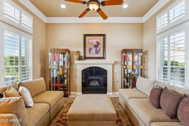 living room featuring ornamental molding, a tile fireplace, and ceiling fan