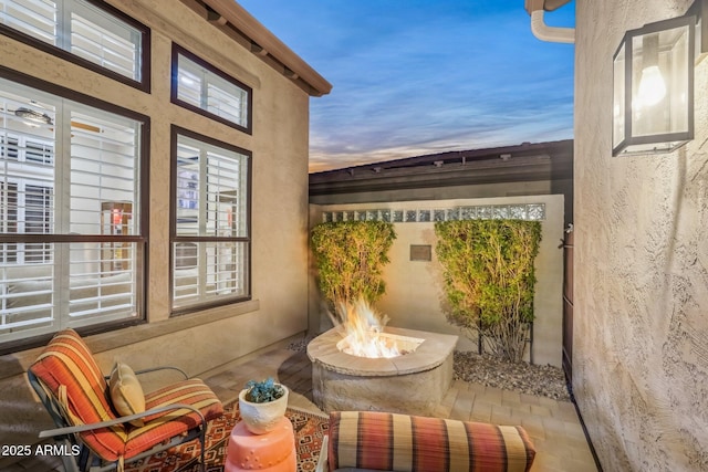 balcony at dusk with an outdoor fire pit and a patio area