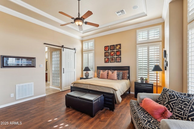 bedroom featuring a raised ceiling, crown molding, a barn door, and dark hardwood / wood-style floors