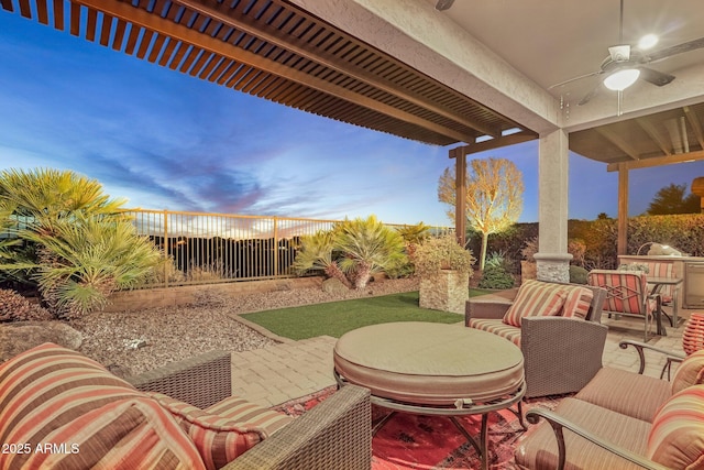 patio terrace at dusk featuring ceiling fan and an outdoor hangout area