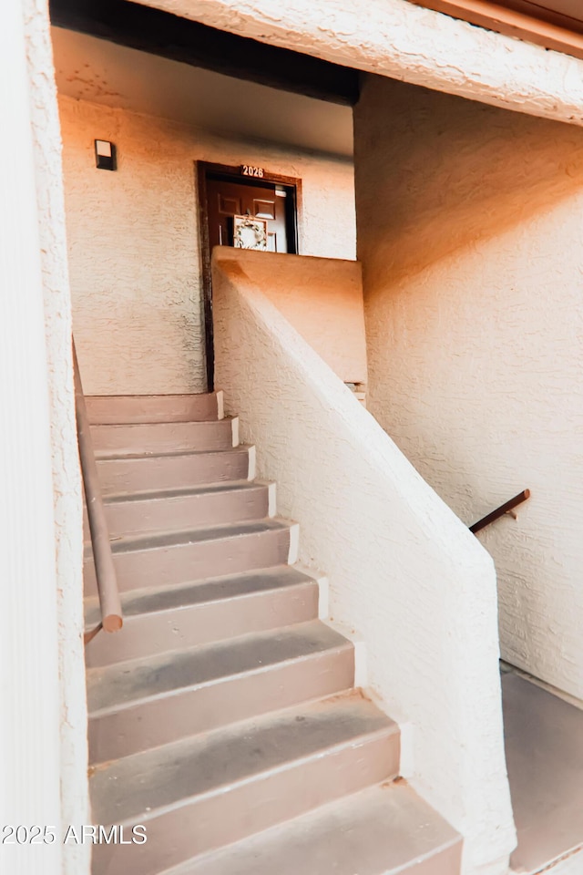 stairway featuring a textured wall