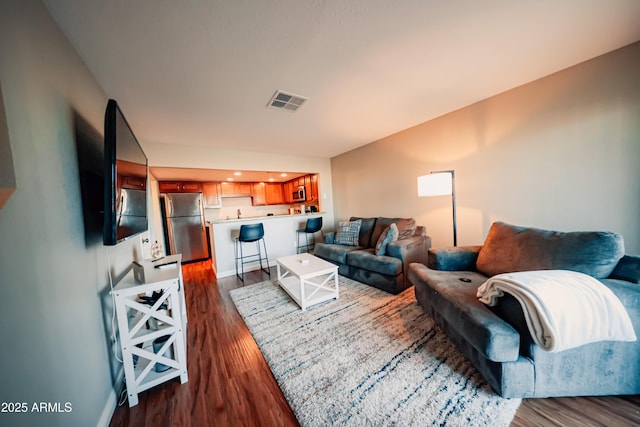 living room with visible vents, baseboards, and dark wood finished floors