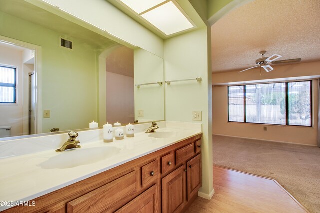 full bathroom featuring double vanity, visible vents, a textured ceiling, and a sink