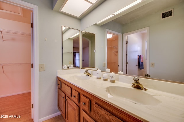 bathroom featuring a sink, visible vents, wood finished floors, and double vanity