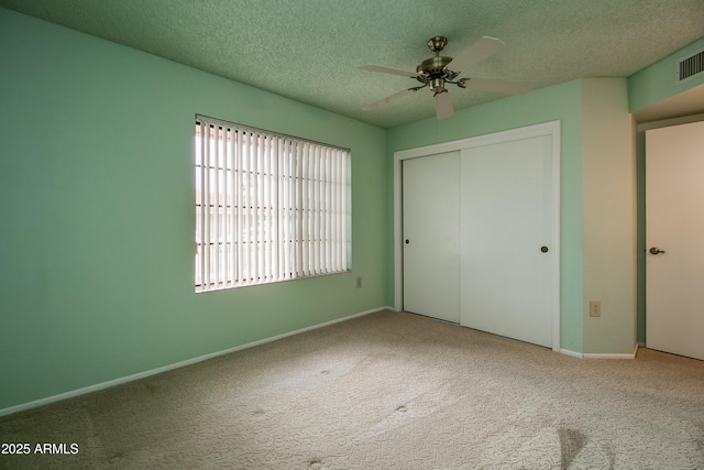 unfurnished bedroom featuring a closet, carpet floors, a textured ceiling, and baseboards