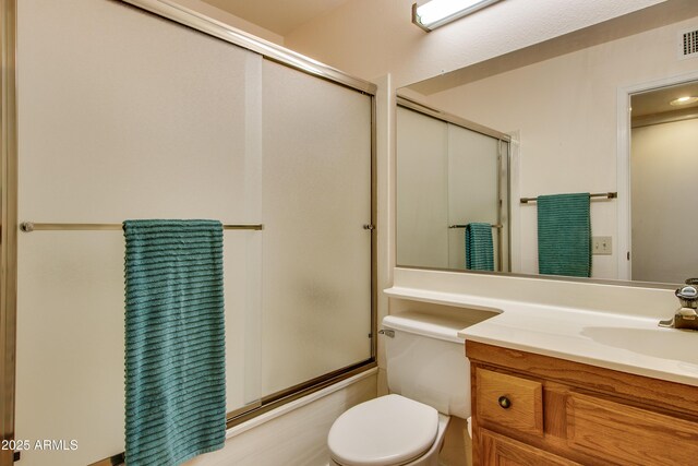 bathroom featuring combined bath / shower with glass door, toilet, and vanity