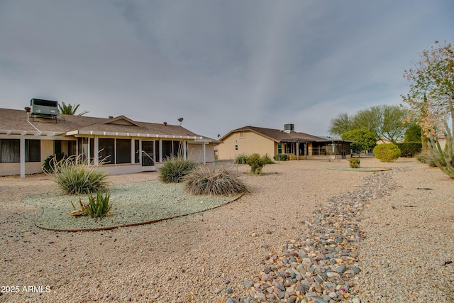 back of property with central AC unit, a sunroom, and stucco siding