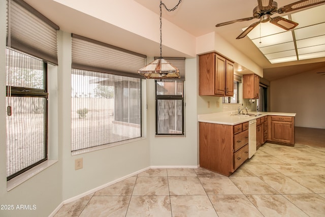 kitchen with a sink, light countertops, white dishwasher, and brown cabinets