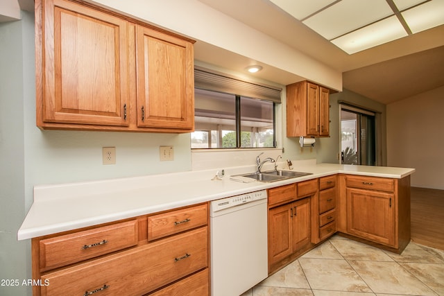 kitchen with dishwasher, light countertops, light tile patterned floors, a peninsula, and a sink